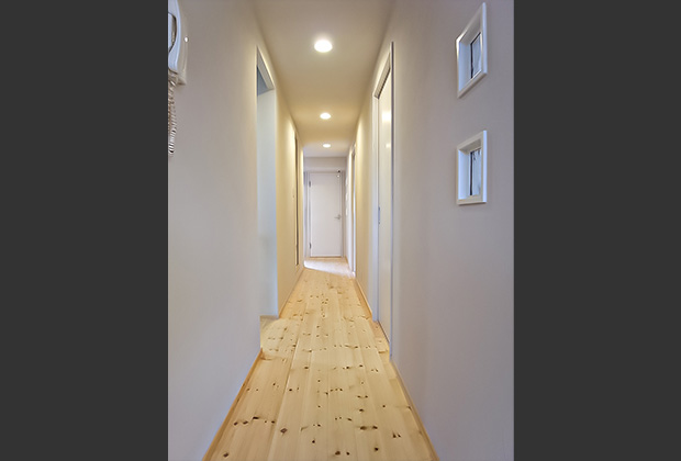廊下after：床は明るい色の無垢パイン材を使用。壁のガラスブロックが隣の部屋の光も取り込み明るい空間に。