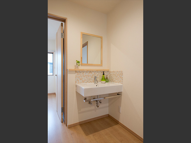 2階の廊下にも造作洗面台を設置しました。オレンジ色のモザイクタイルと木のフレームの鏡がおしゃれ。