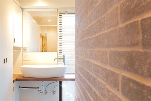 玄関へ通じる廊下にある洗面台は、窓際のロングカウンターから続いており、窓前の気持ちの良い場所に。